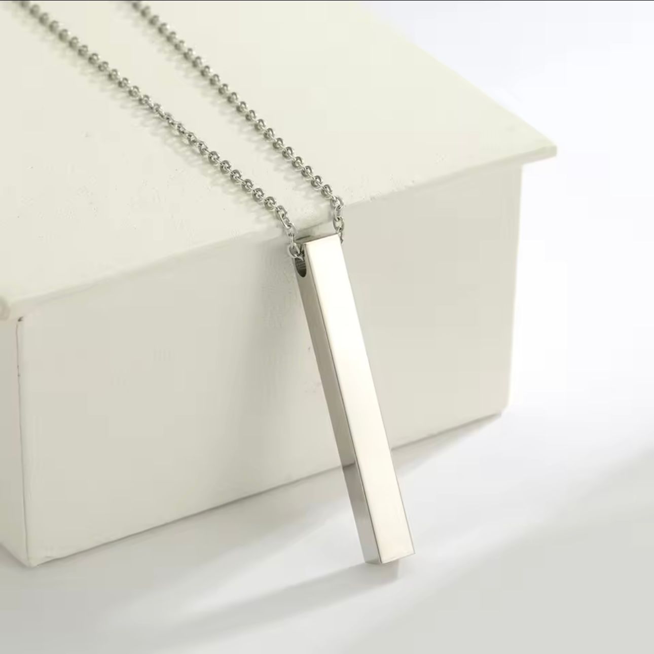 A gold-plated bar necklace with engraved names on it, displayed on a white background.