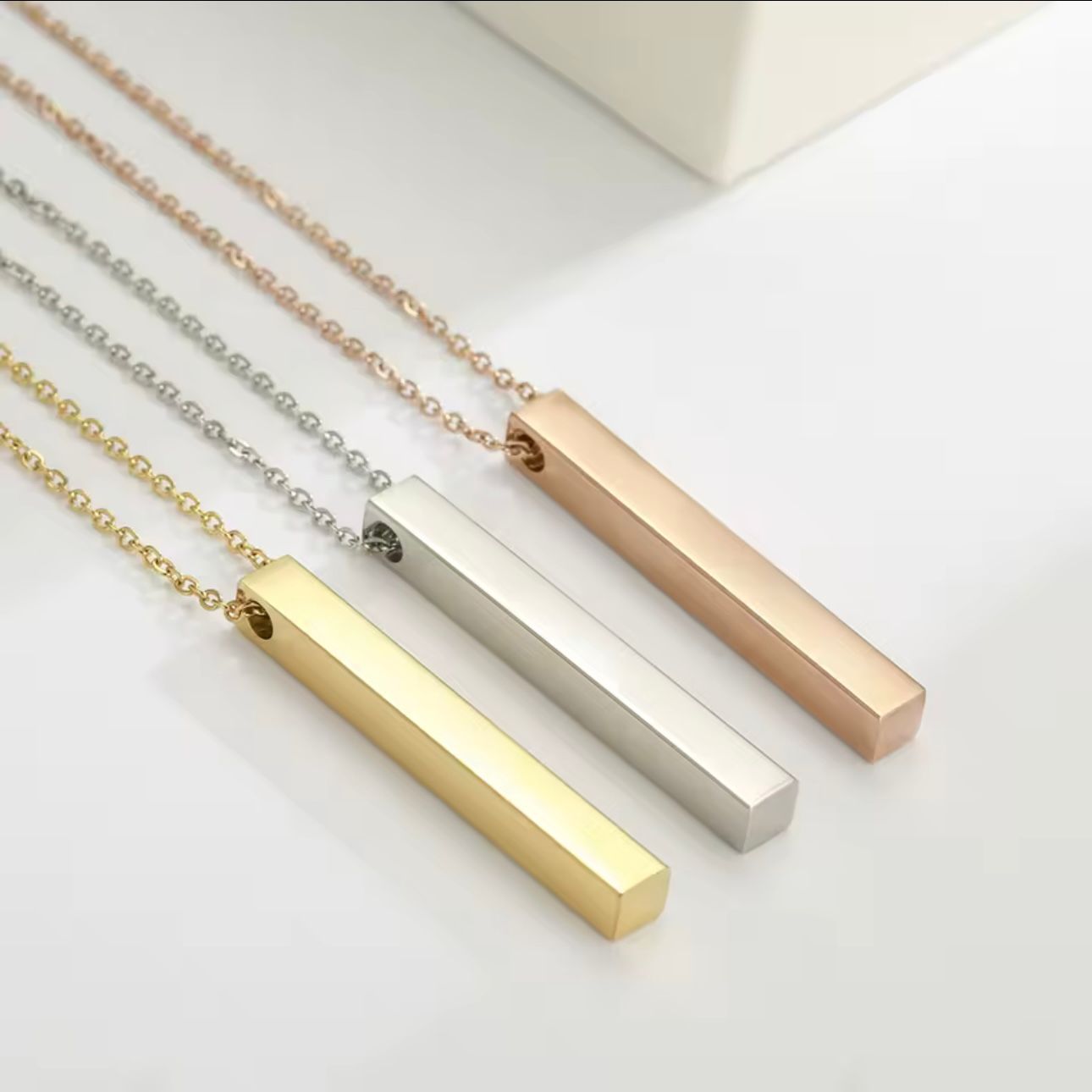 A collection of gold-plated bar necklaces with engraved names on it, displayed on a white background.