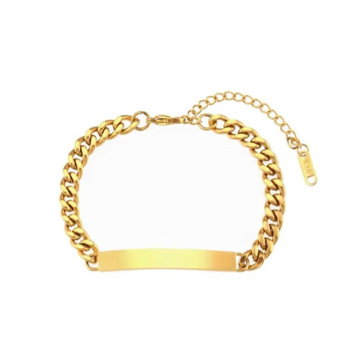 A gold-colored stainless steel bracelet with a curb chain design and an engraved bar pendant in the center.