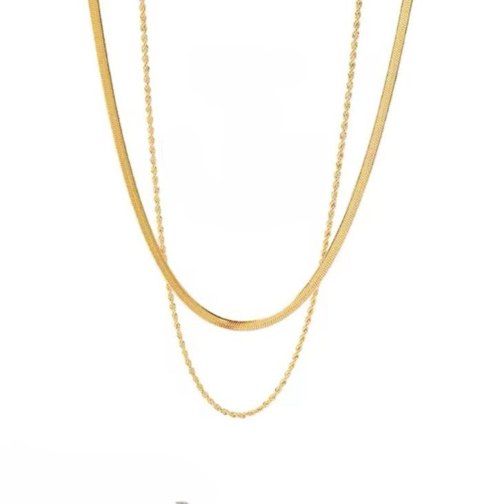 A gold colored twin chain necklace displayed over white background.