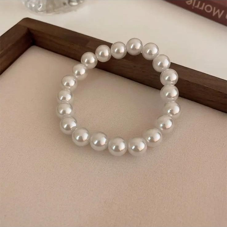 A bracelet made of luminous freshwater pearls displayed on a flat surface.