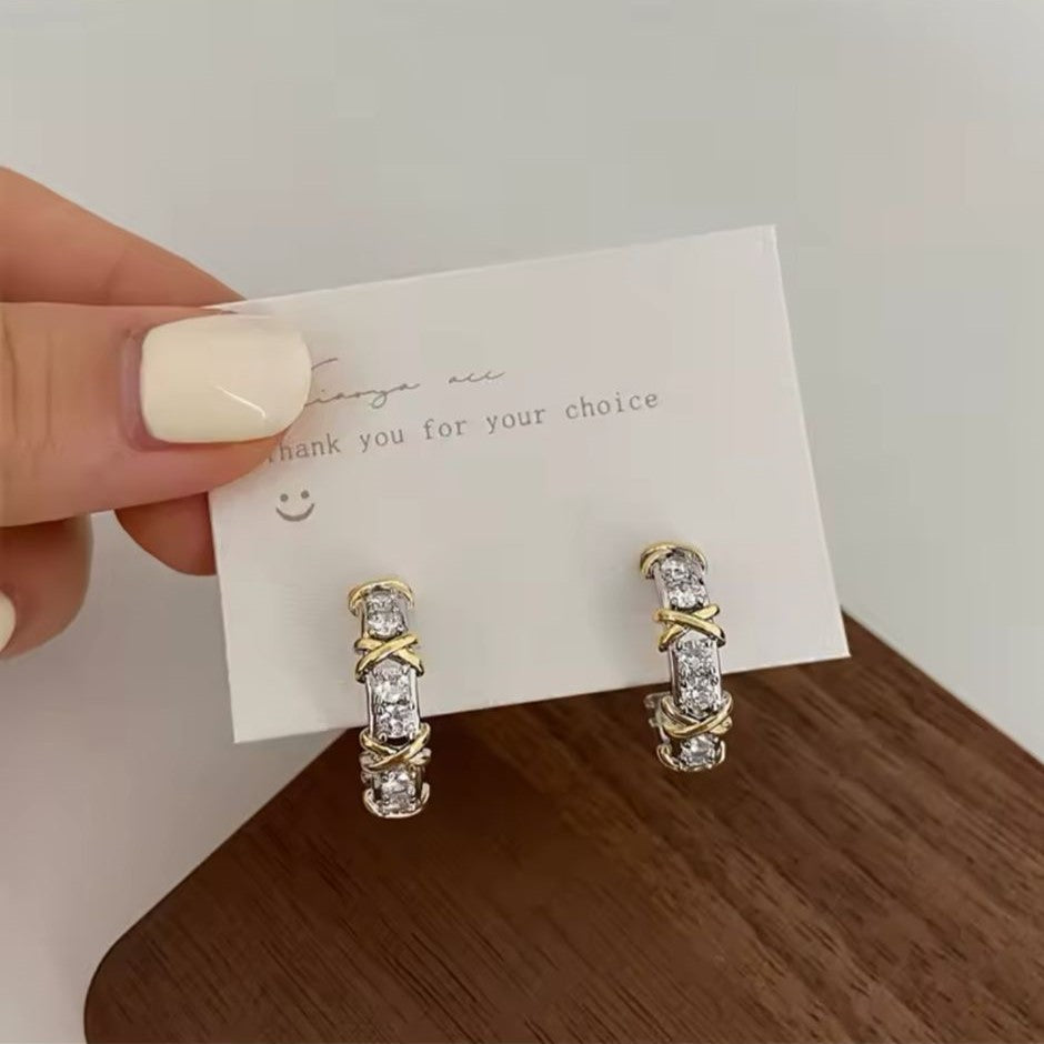 A pair of gold & silver-tone hoop earrings adorned with sparkling crystals and featuring a unique 'X' detailing.