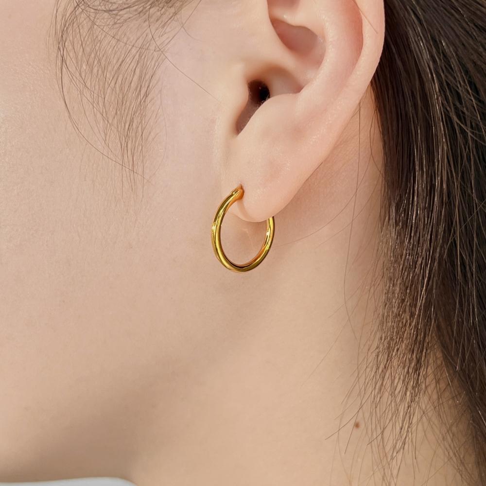 A gold hoop earring made of 925 sterling silver with 18k gold plating, displayed on women's ear.