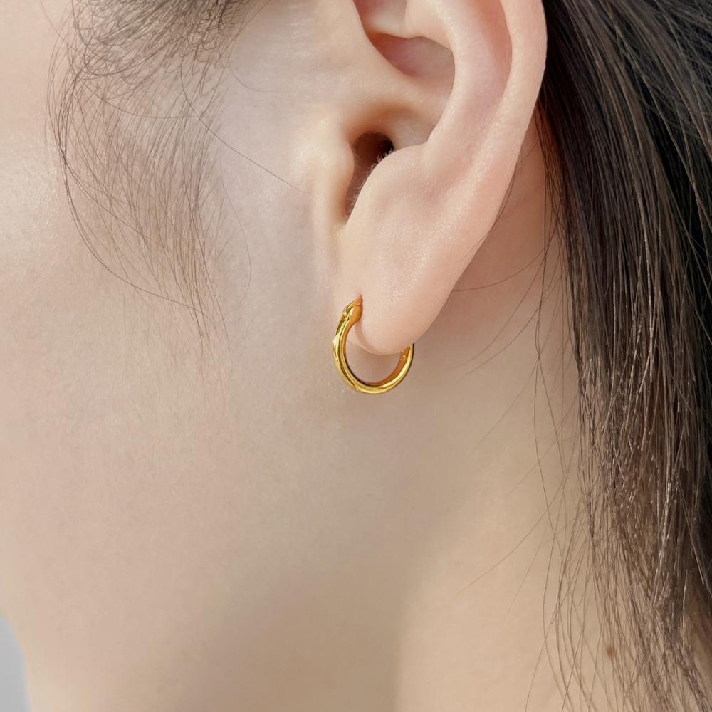 A gold hoop earring made of 925 sterling silver with 18k gold plating, displayed on women's ear.
