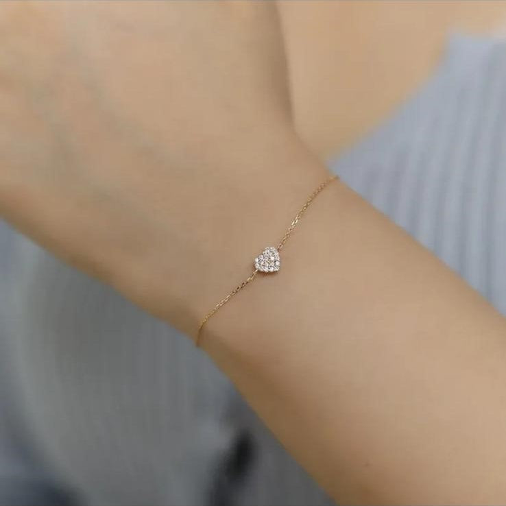 A sterling silver bracelet with a gold plated zirconia heart design, displayed on a wrist.