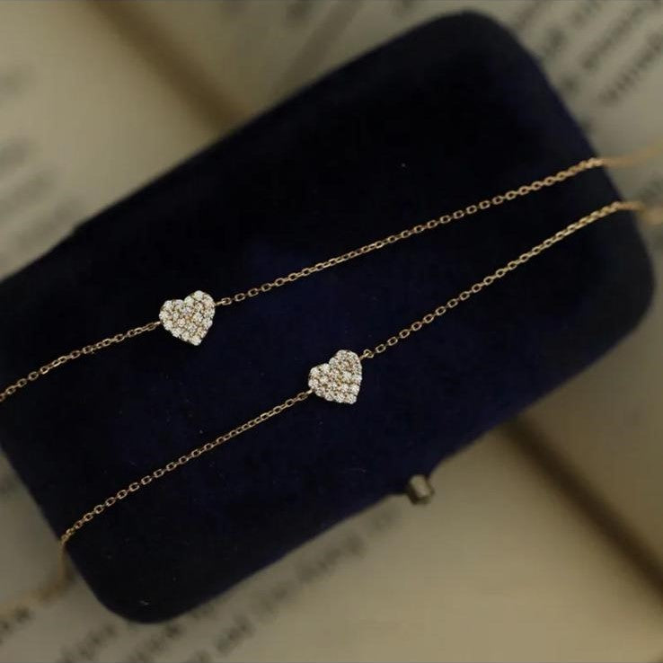 Two sterling silver bracelets with a gold plated zirconia heart design, displayed on black.