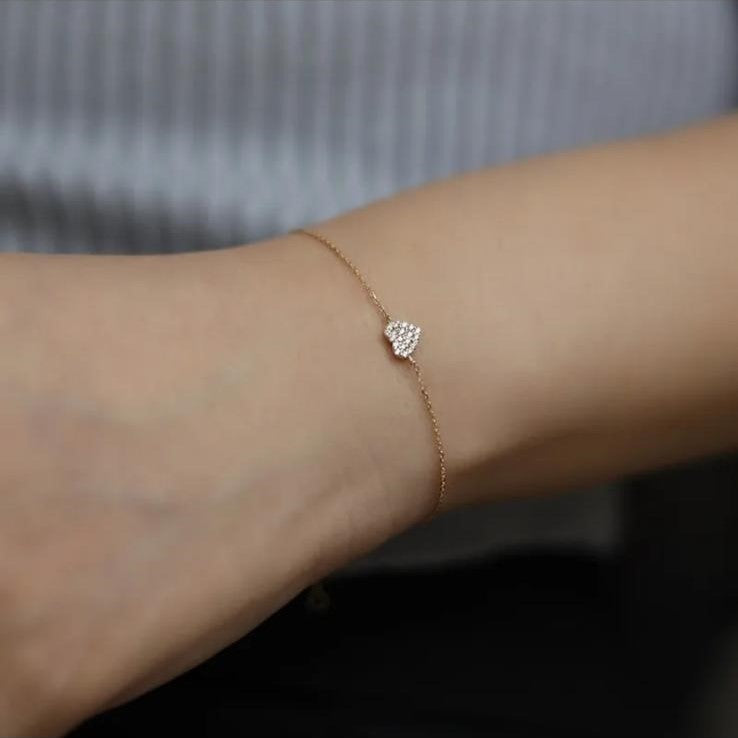 A sterling silver bracelet with a gold plated zirconia heart design, displayed on a wrist.