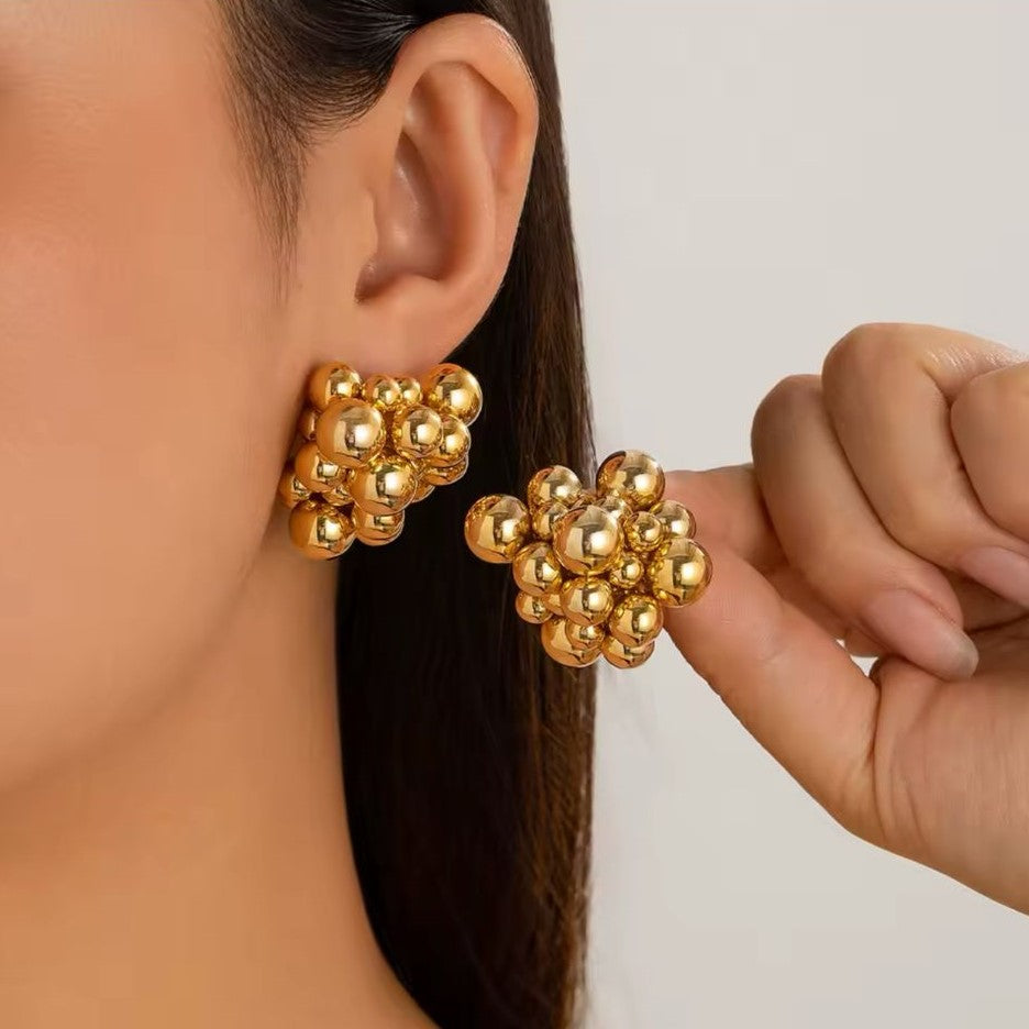 A pair of premium quality Honeycomb style Gold Earrings presented on a women's ear.