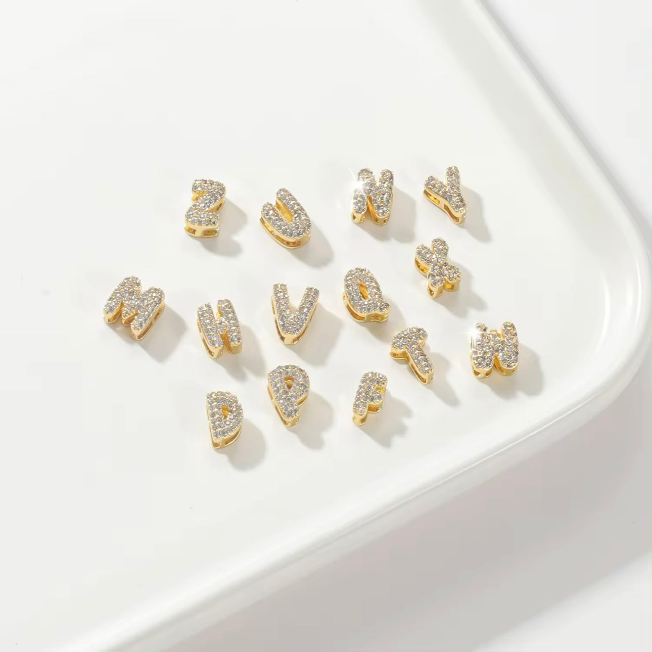 Personalized bubble letters for charm necklace in gold tone, displaying charms, set against a white background.