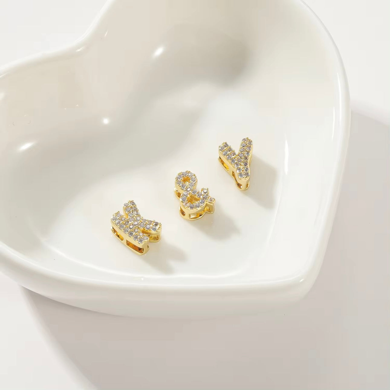Personalized bubble letters for charm necklace in gold tone, displaying charms, set against a white background.