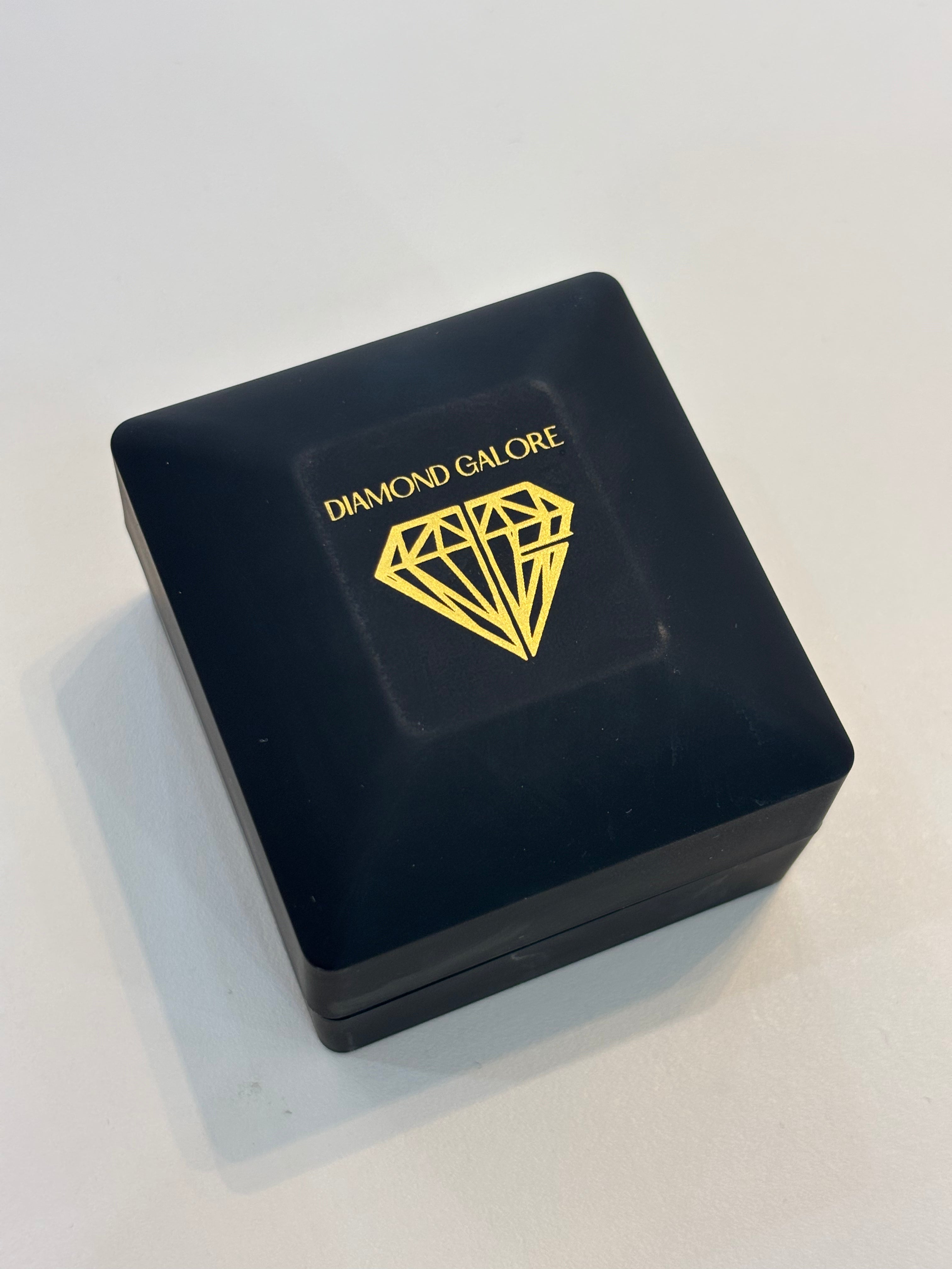 A black ring box with the brand name 'Diamond Galore' written in gold. The box is closed and positioned on a white surface.