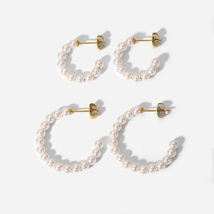 A set of pearl hoop earrings with a stainless steel C-shape design, displayed in a silver color.