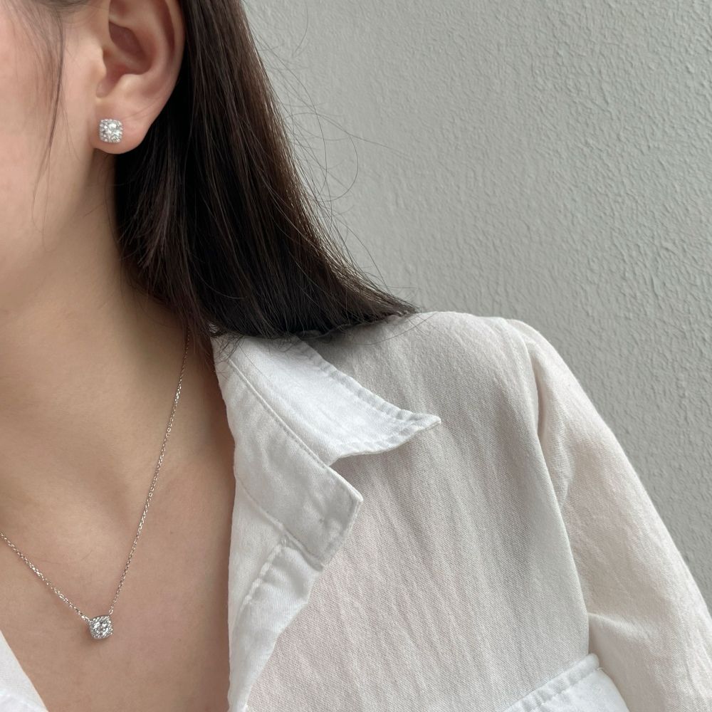 A sterling silver pendant necklace with a central sparkling stone surrounded by smaller stones, attached to a rhodium-plated chain.