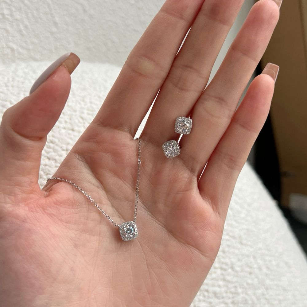A sterling silver pendant necklace with a central sparkling stone surrounded by smaller stones, attached to a rhodium-plated chain along with earrings.