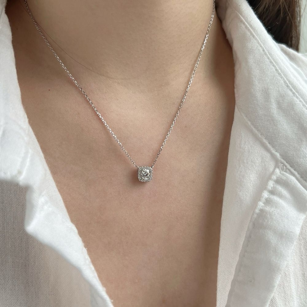 A sterling silver pendant necklace with a central sparkling stone surrounded by smaller stones, attached to a rhodium-plated chain.