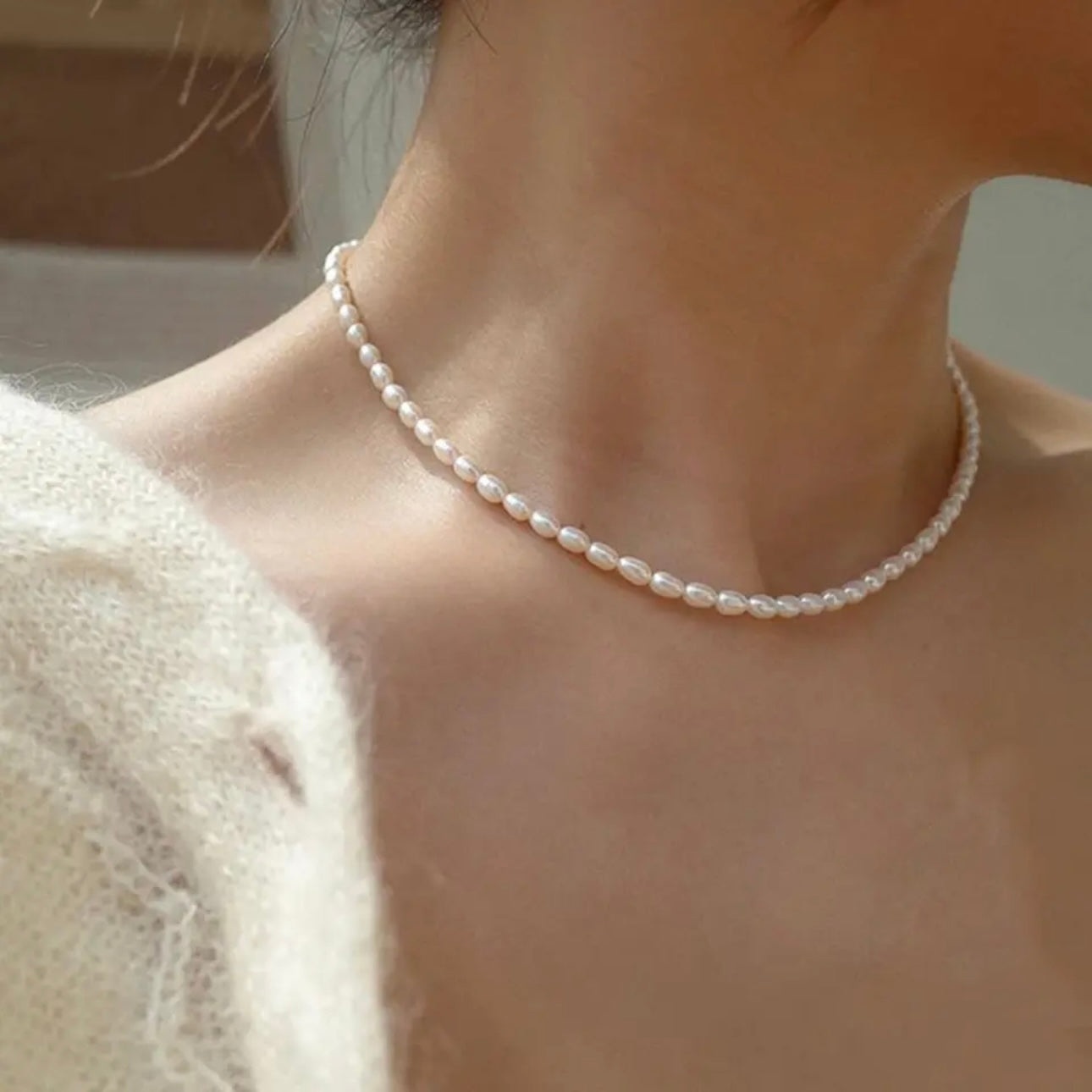 A pearl necklace with multiple small white pearls chain displayed on a women's neck.