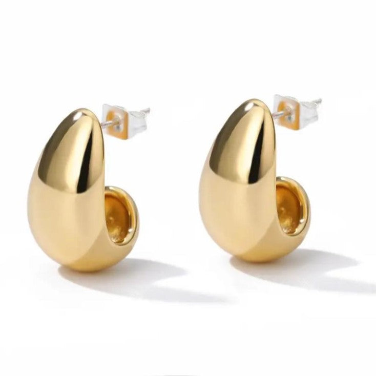 A pair of gold-colored, curved hoop earrings on a white background.