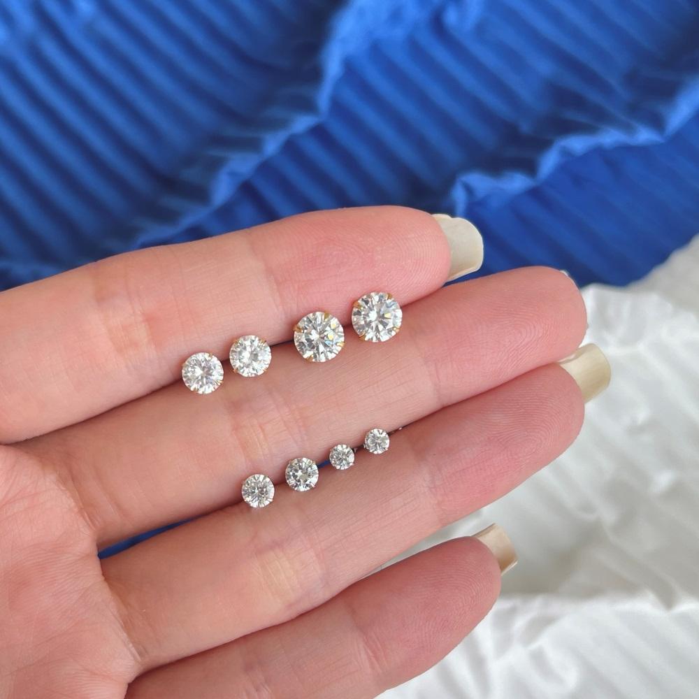 Four sets of gold-plated barbell stud earrings featuring clear, faceted gemstones.
