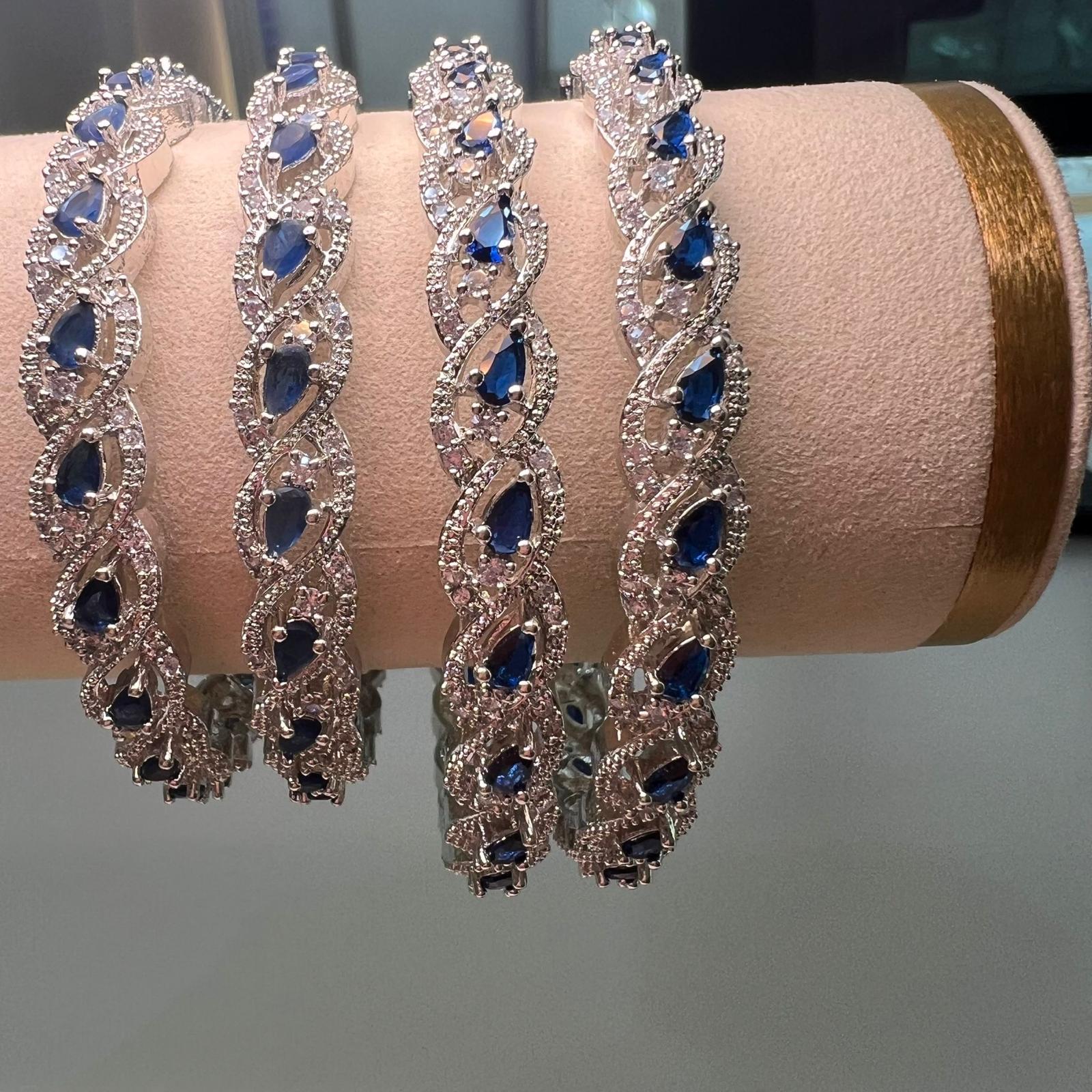 Four Silver bracelets with blue stones on a pink cushion