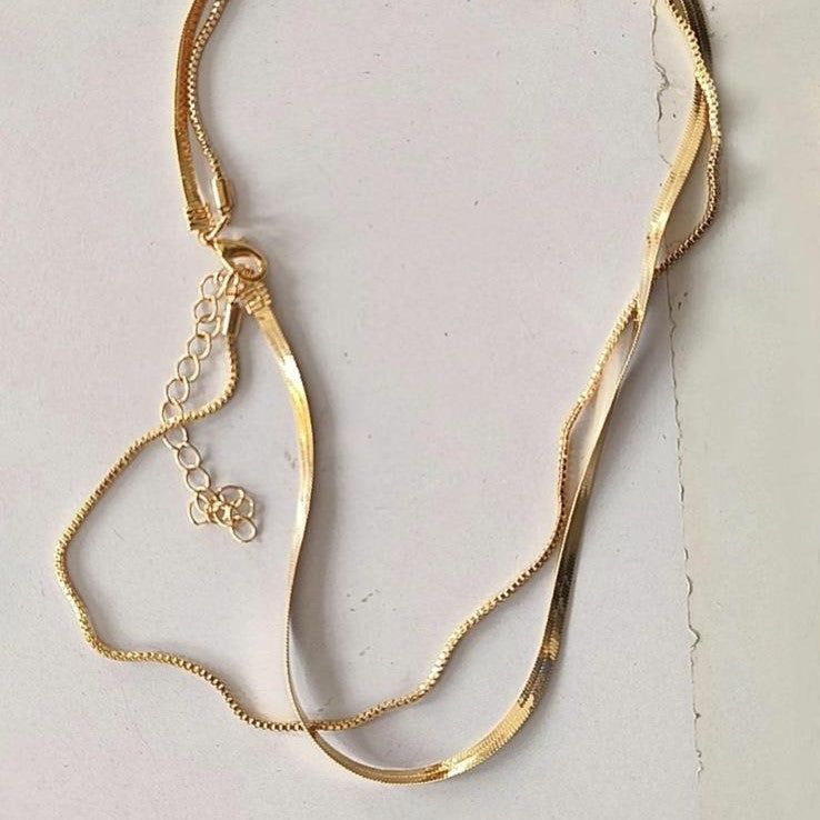 Two layered flat snake chain necklaces in gold tone, displayed against a white background.