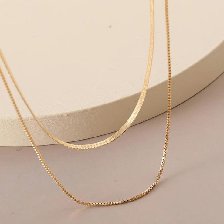 Two layered flat snake chain necklaces in gold tone, displayed against a white background.