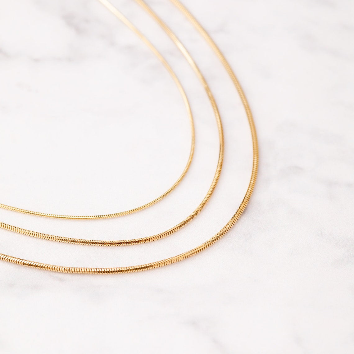 A gold-colored snake chain bracelet.
