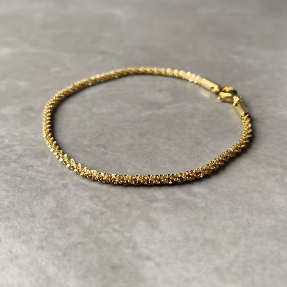Gold colored spiral bracelet on a gray background
