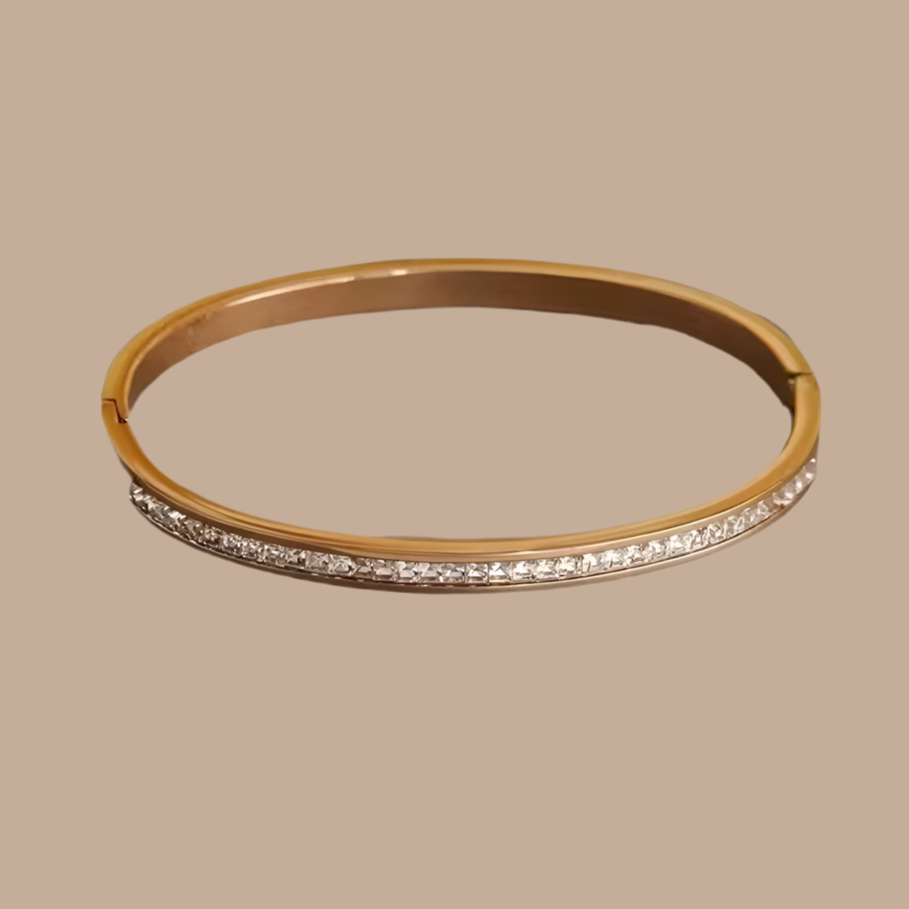 Gold bracelet with diamond accents on a beige background