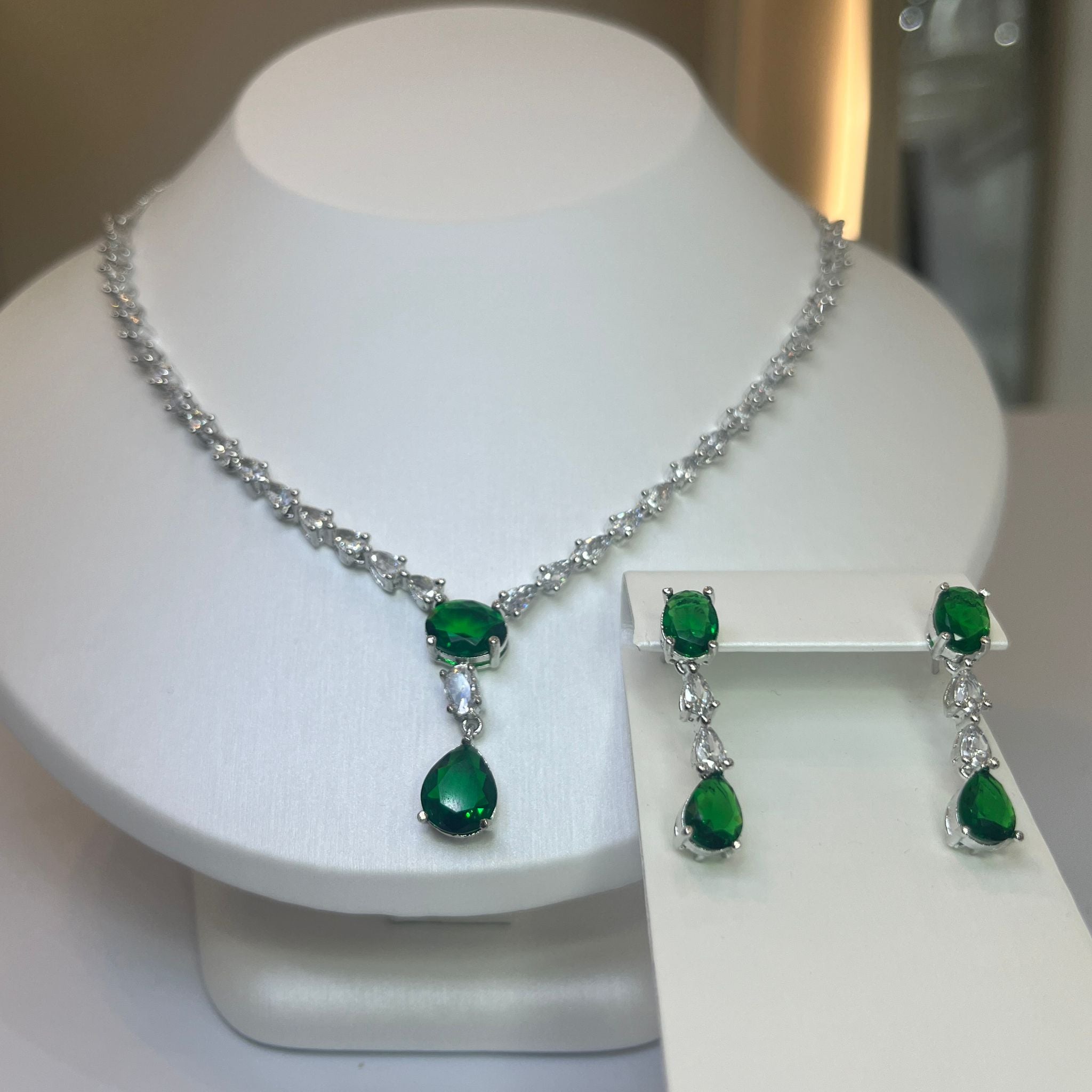 A teardrop necklace and earrings set displayed on a white mannequin. The set features a silver-tone chain with crystal embellishments and a teardrop pendant.