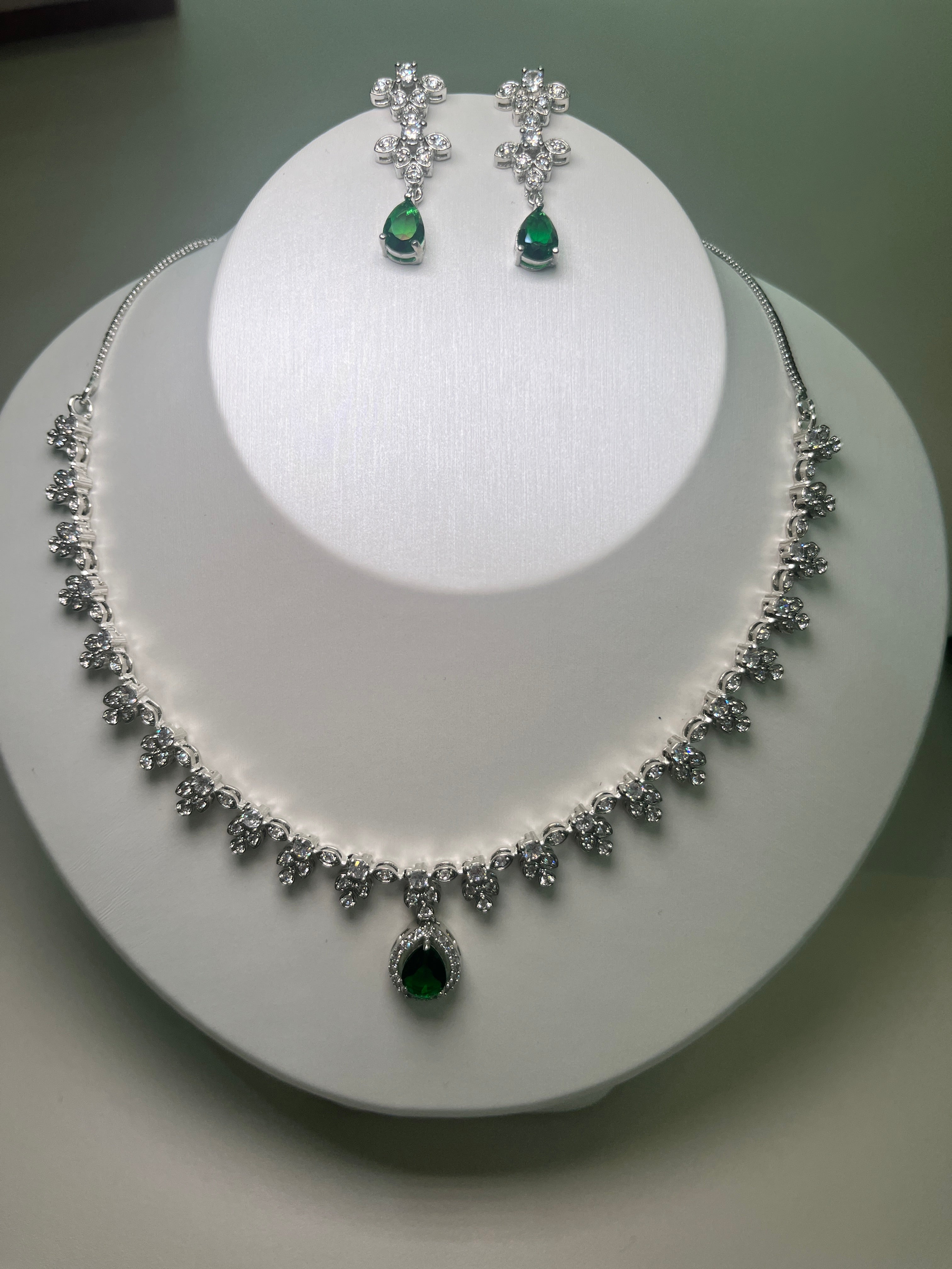 A necklace and earrings set featuring a teardrop-shaped gemstone centerpiece with a silver-tone finish, displayed on a mannequin bust.