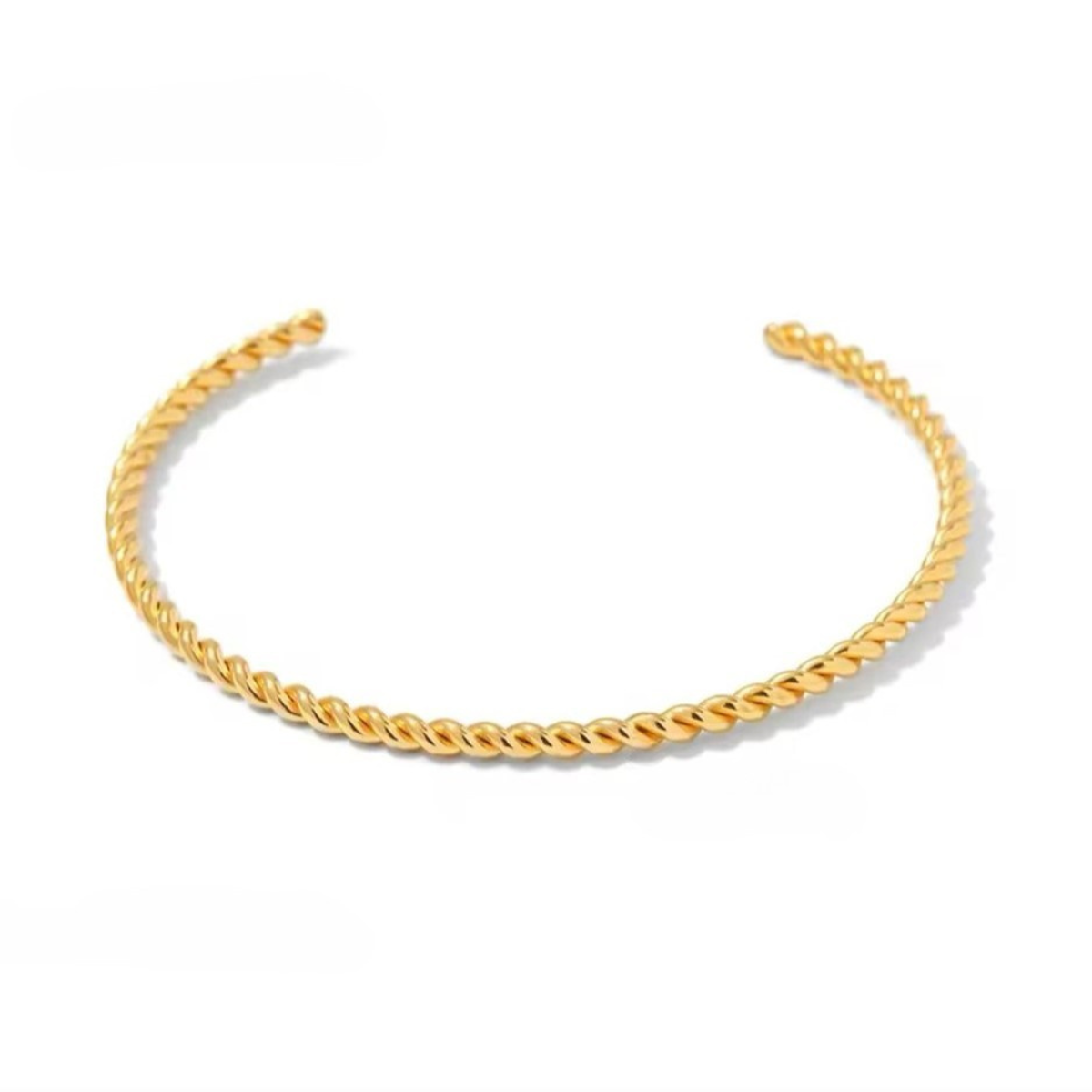 A gold-colored bangle with a twisted design, displayed against a white background.