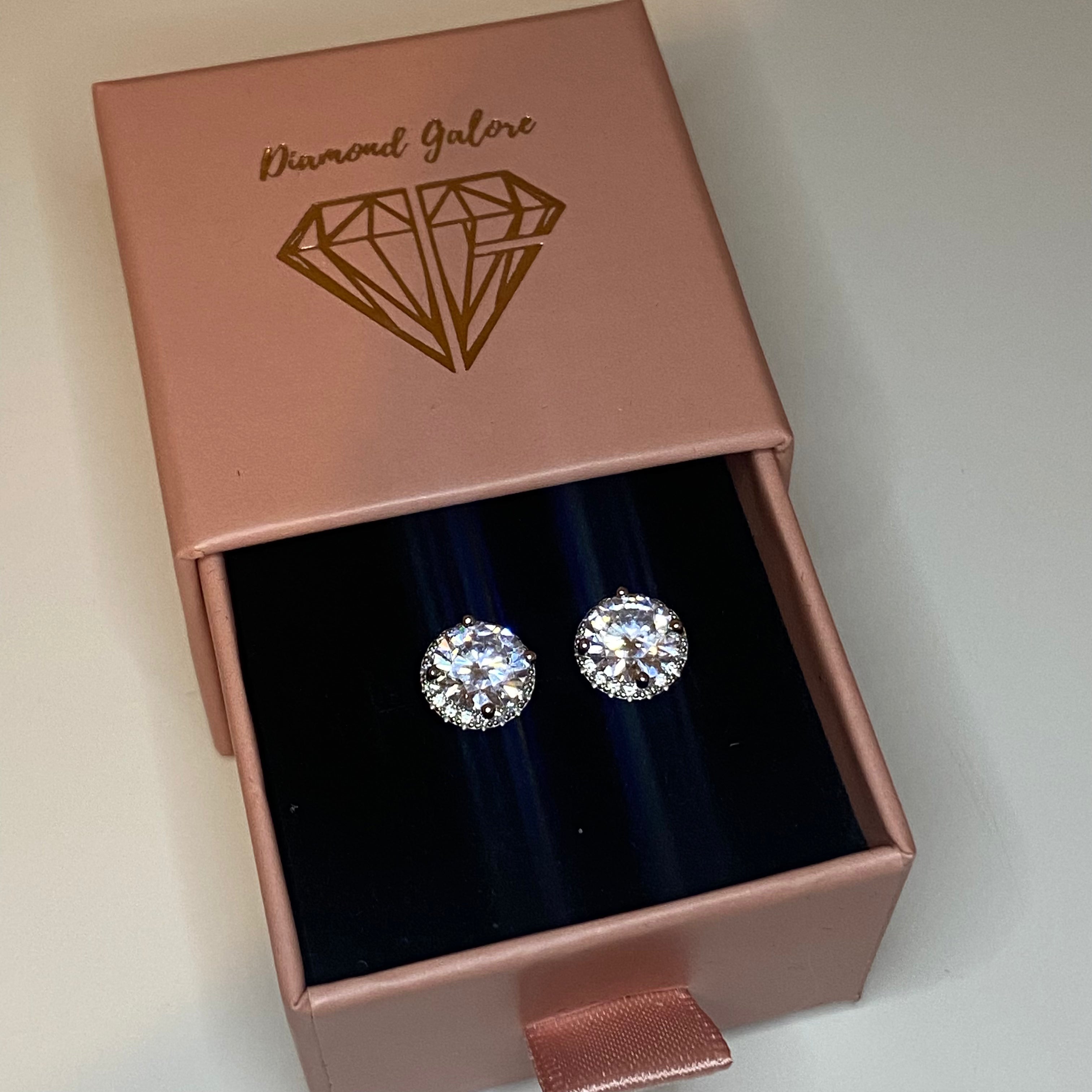 A pair of rhodium-plated stud earrings with a clear, zirconia main stone set in a small circle design.