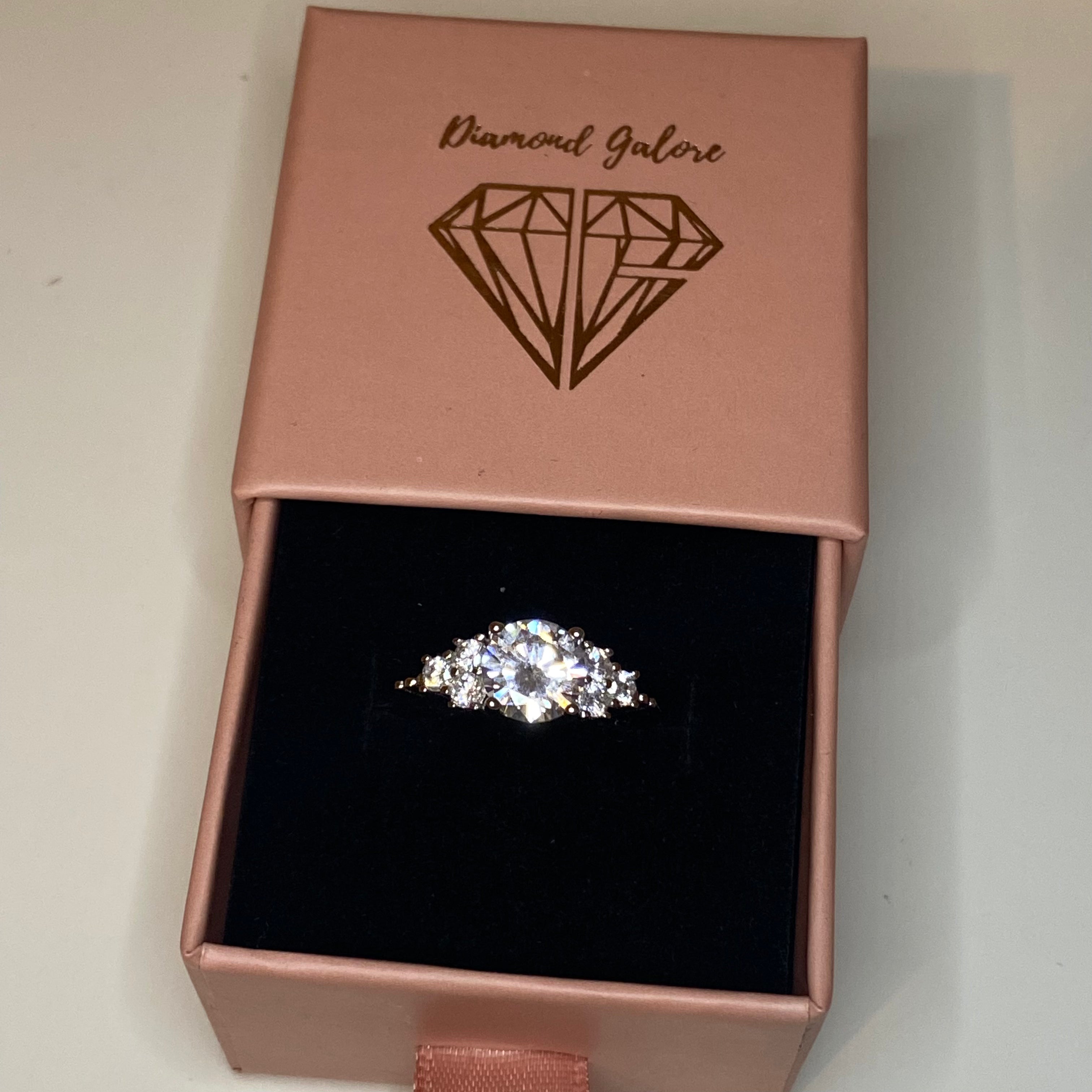 An elegant sterling silver ring with a large central clear cubic zirconia stone, surrounded by smaller clear stones, set in a gold-tone band.