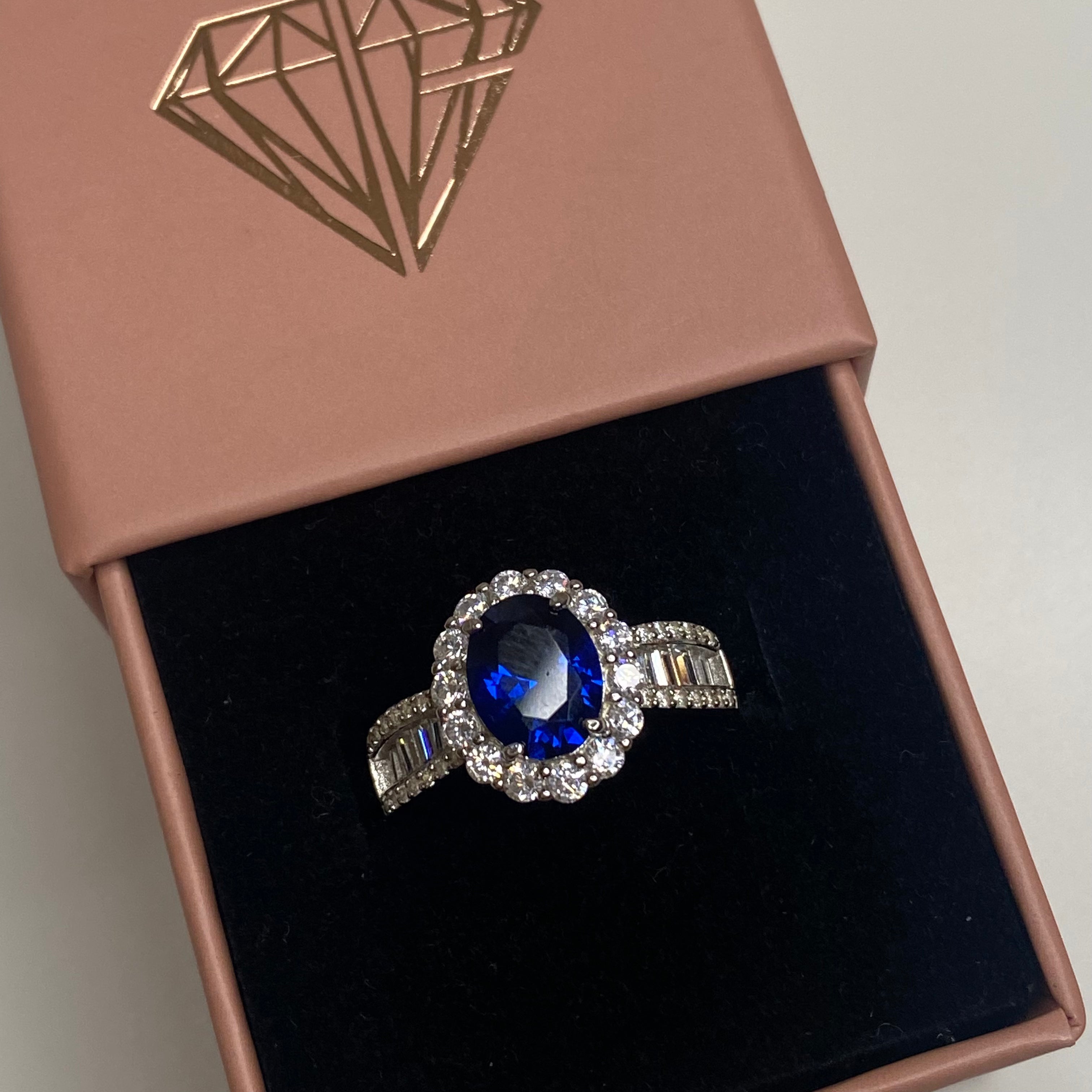 An elegant sterling silver ring featuring an oval blue zircon stone with smaller clear stones around it, showcasing a traditional Indian royalty-inspired design.