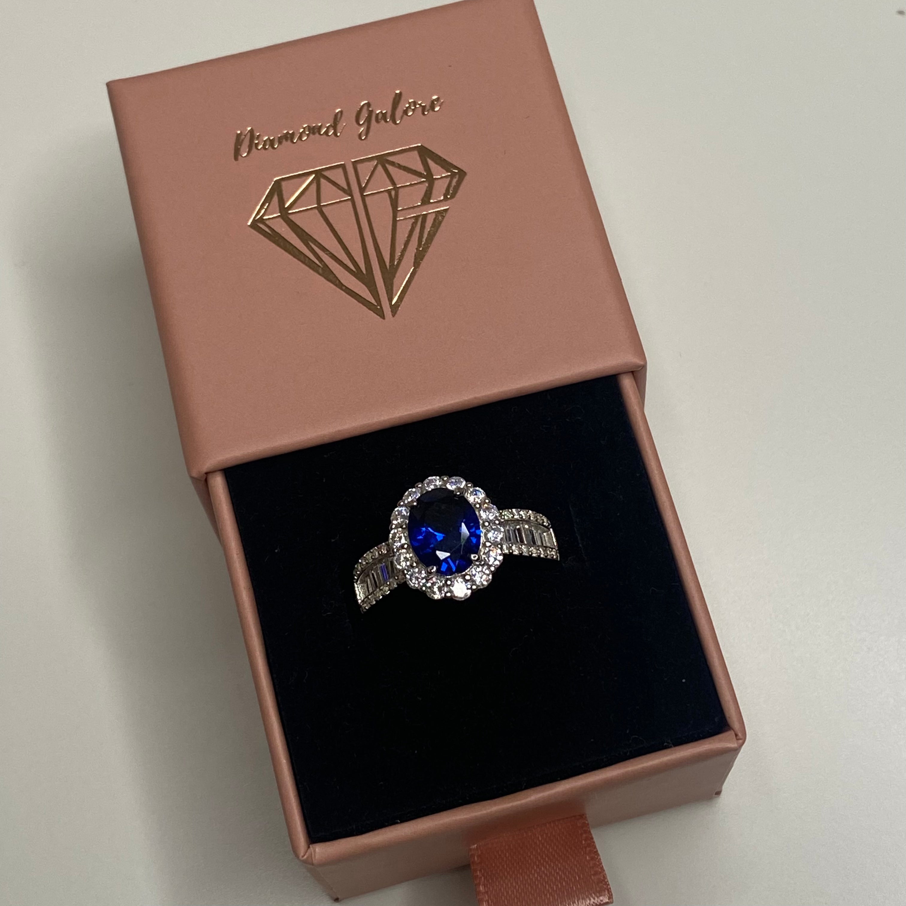 An elegant sterling silver ring featuring an oval blue zircon stone with smaller clear stones around it, showcasing a traditional Indian royalty-inspired design.