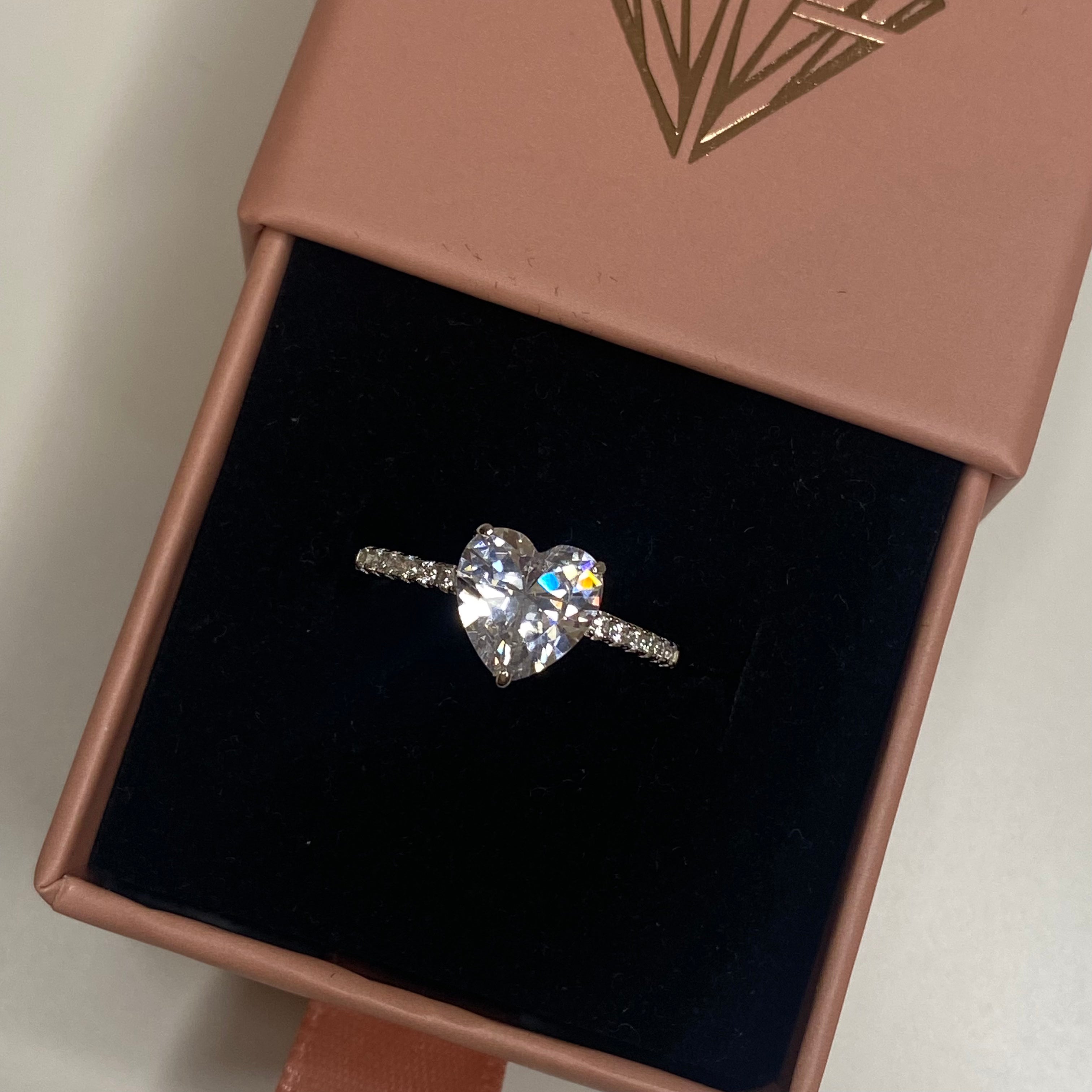 A heart-shaped 5A CZ silver ring with big and small white stones on the band, displayed against a white background.