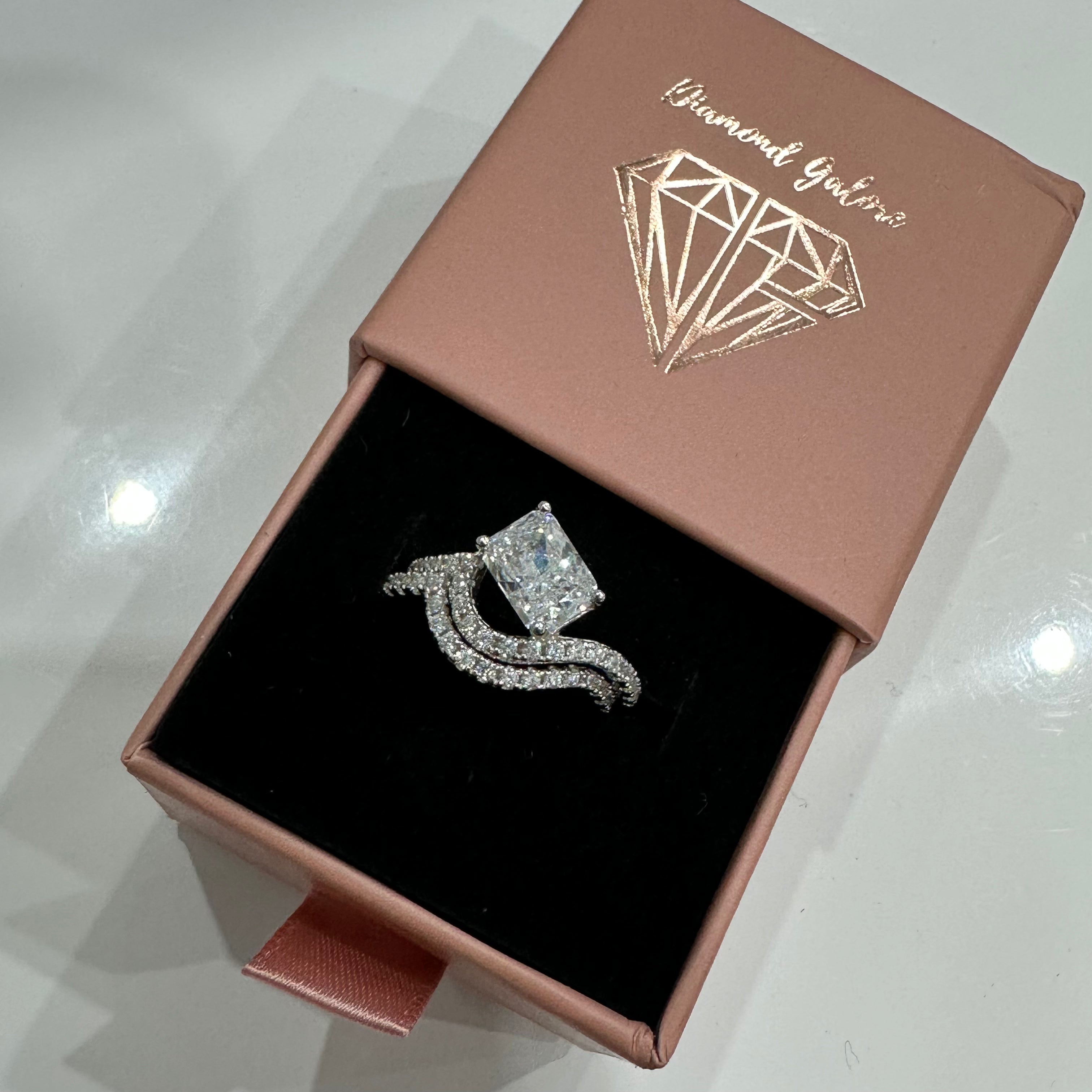 A sterling silver ring featuring a main stone (clear-color), shaped as a rectangle and set with smaller round diamonds in a box.