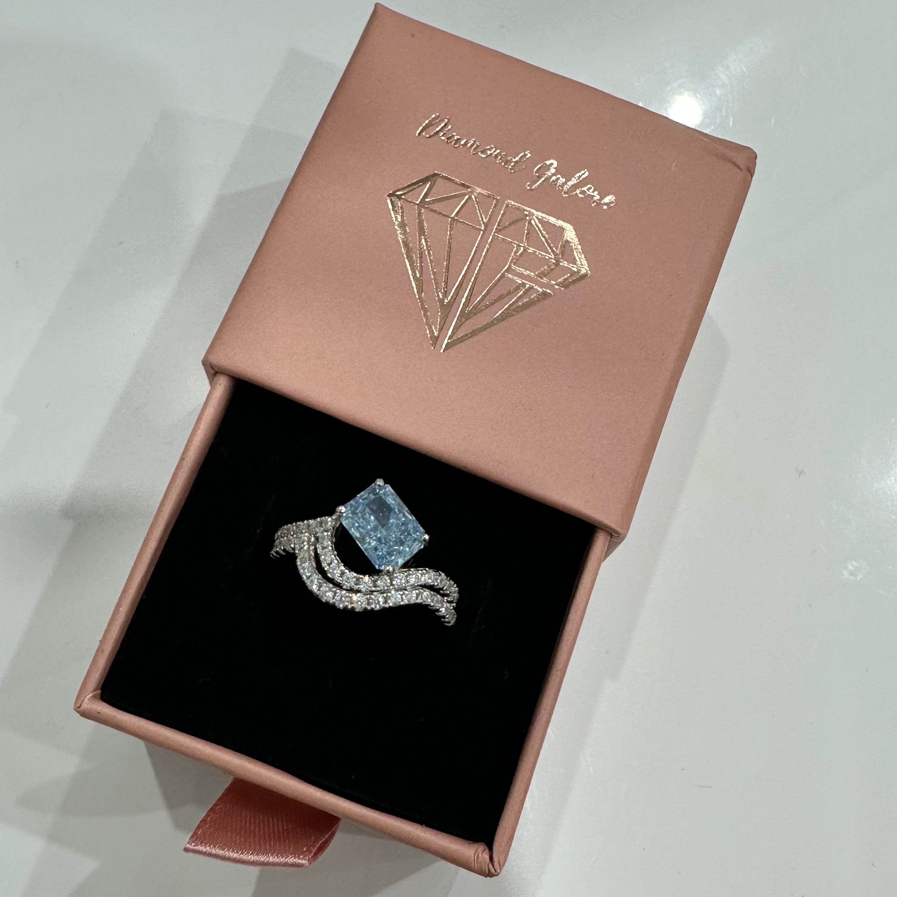A sterling silver ring featuring a main stone (blue-color), shaped as a rectangle and set with smaller round diamonds.