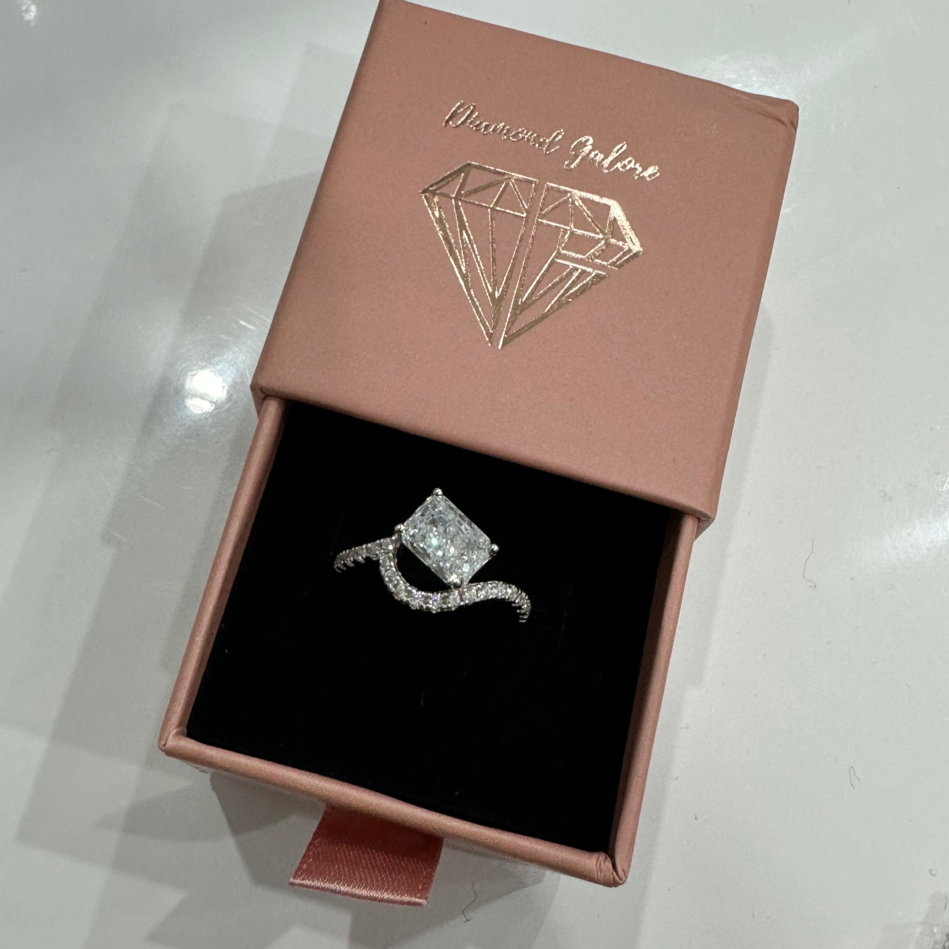 A sterling silver ring featuring a main stone (clear-colored), shaped as a rectangle and set with smaller round diamonds.