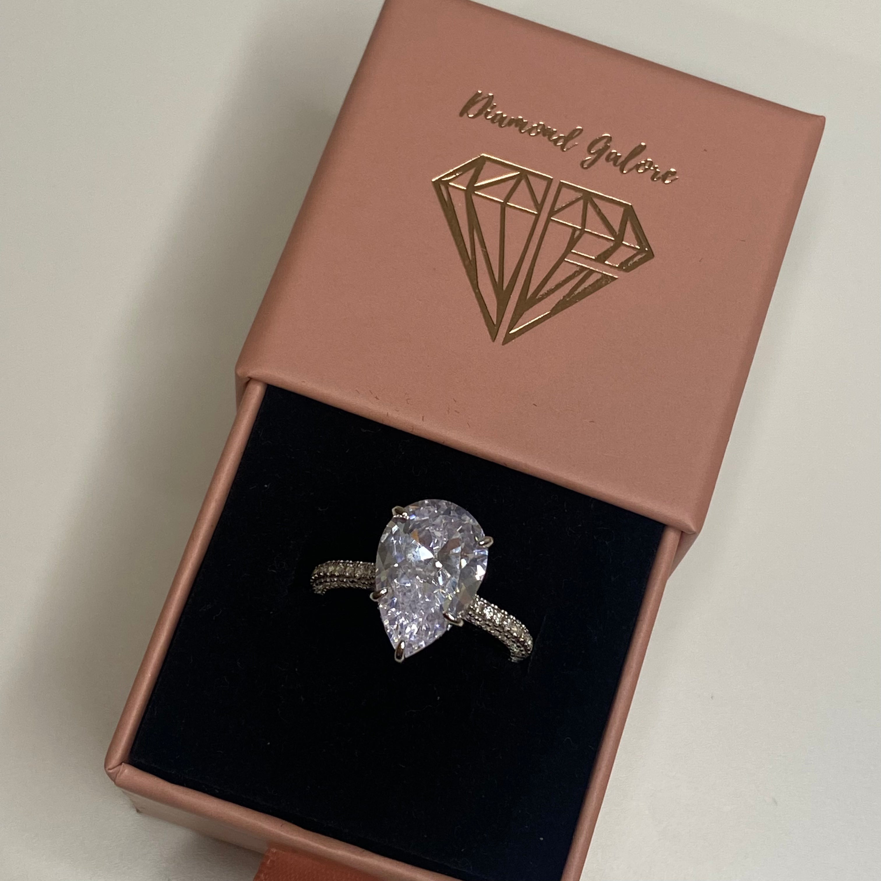 A silver ring with a large pear-shaped clear stone set in the center, with smaller stones around the band.