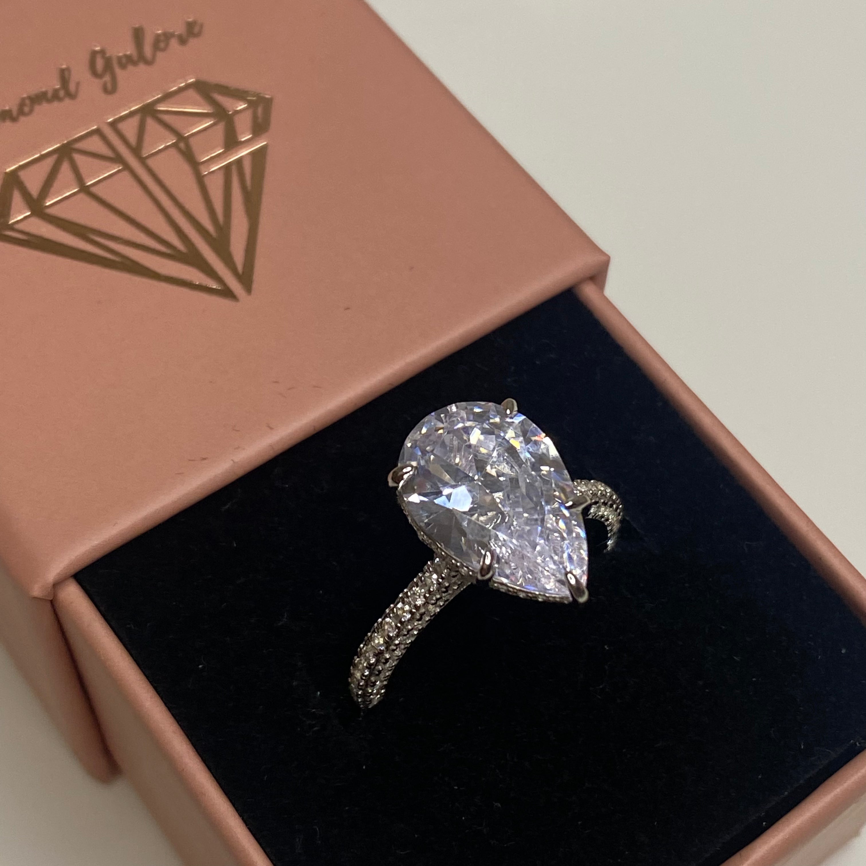 A silver ring with a large pear-shaped clear stone set in the center, with smaller stones around the band.