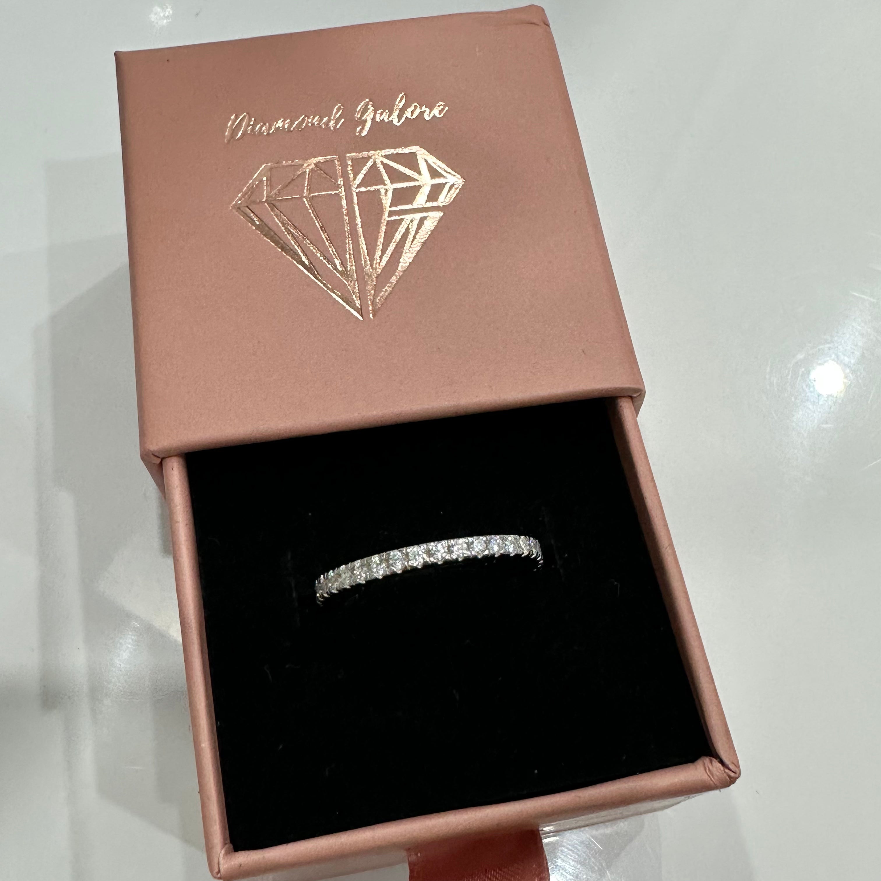 A Sterling Silver band ring with zirconia stones around its circumference on a box.