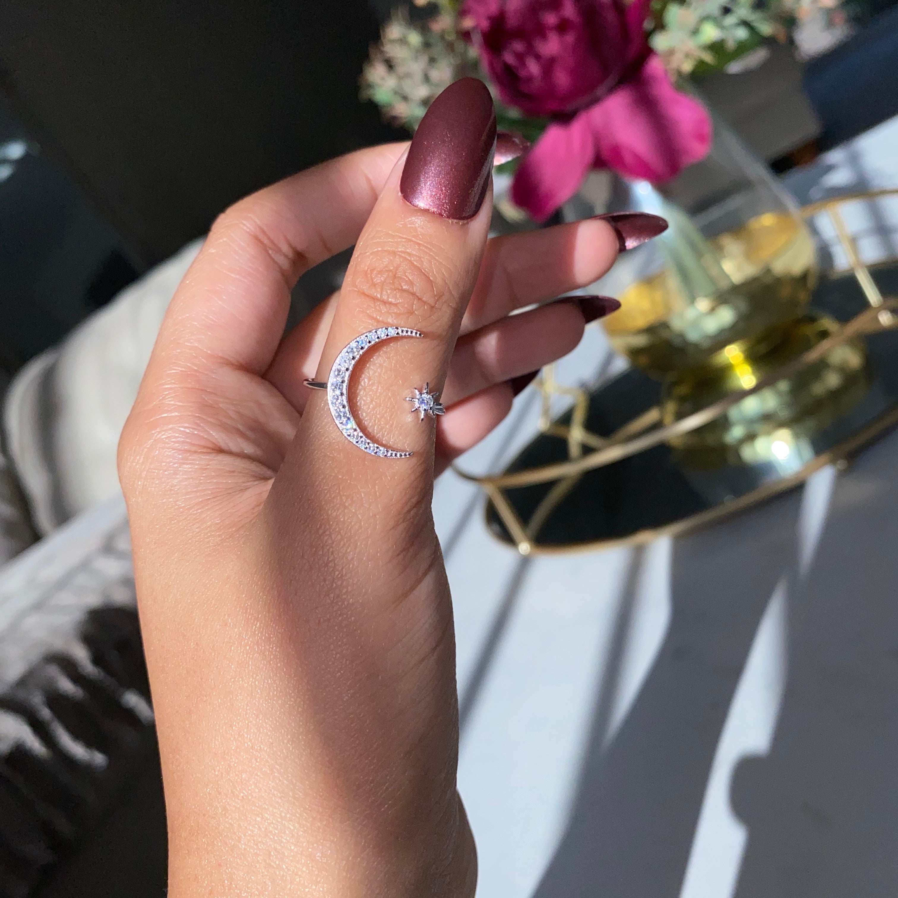 A silver-colored sterling silver ring featuring a crescent moon and a star design with sparkling stones set in the moon and star shapes.