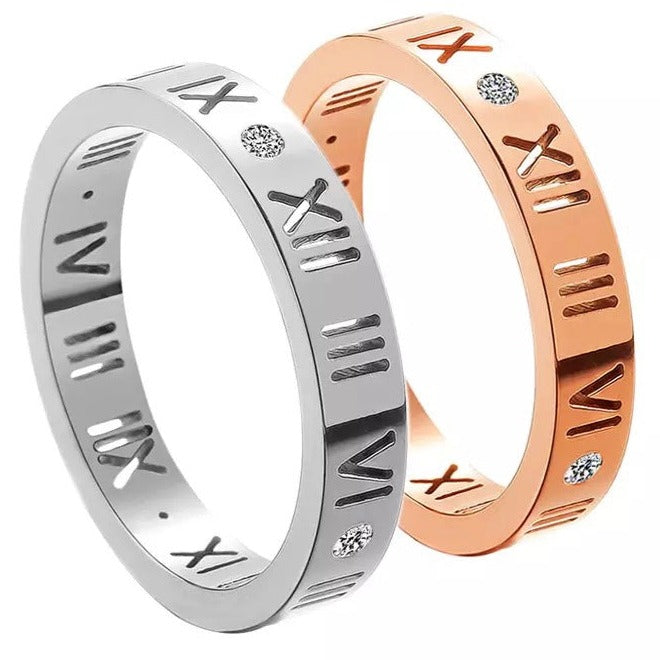 A gold & silver-colored stainless steel band ring with Roman numeral patterns and small embellishments.